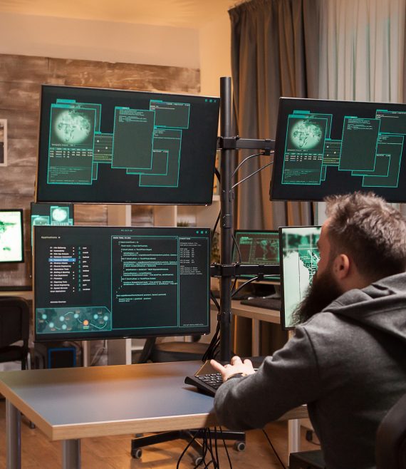 Bearded hacker in a room full of computers