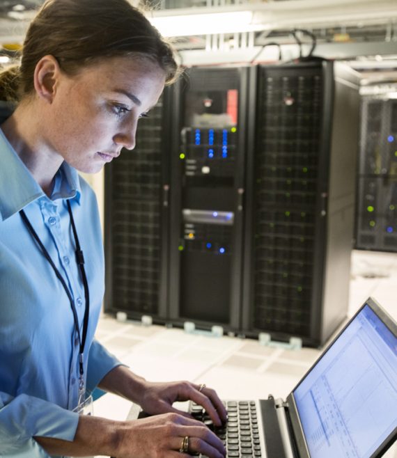 Caucasian woman technician running diagnostics on computer servers in a server farm.